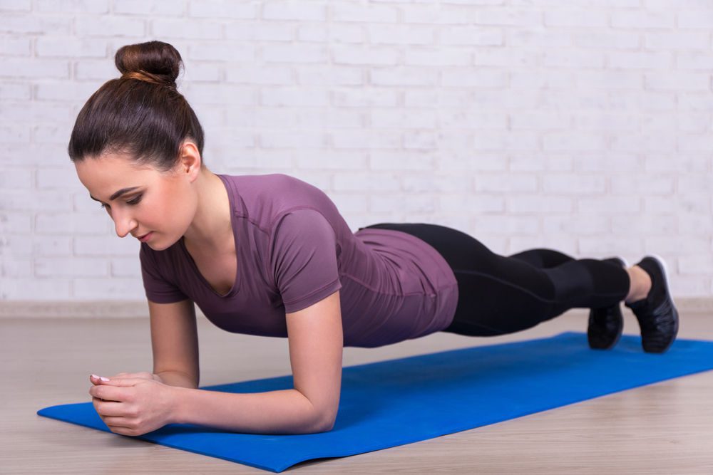 Jeune femme en position de planche (gainage)