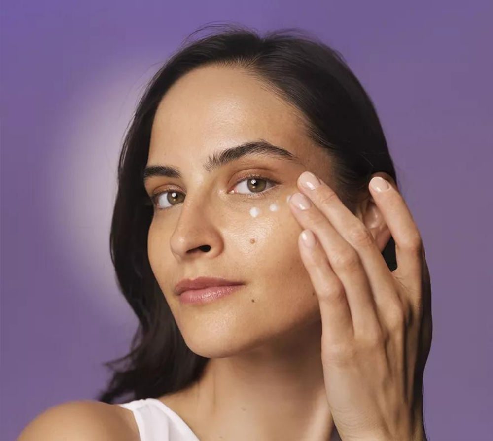 Femme appliquant appliquez une crème nourrissante contour des yeux de la gamme HL/Skin