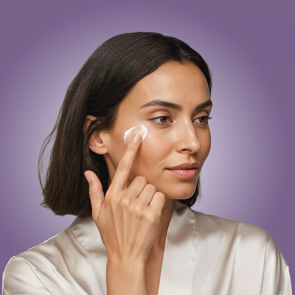 Jeune femme appliquant une crème de nuit sur son visage