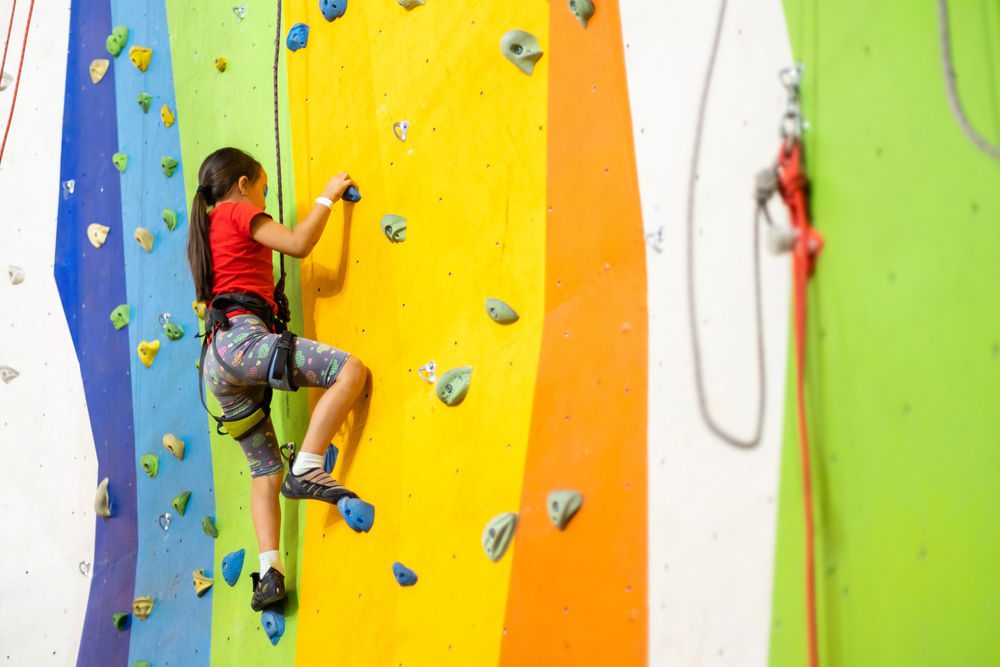 Enfant faisant de l'escalade en salle sur un mur coloré